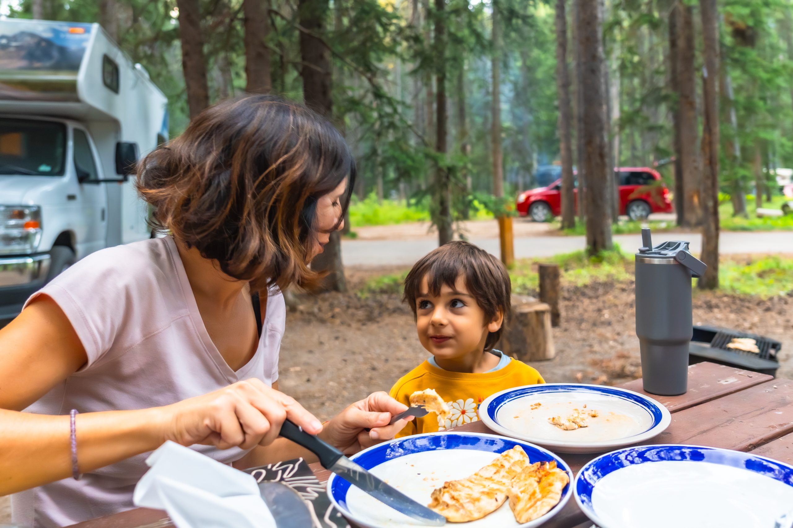Mother giving food to child at campfire in banff n