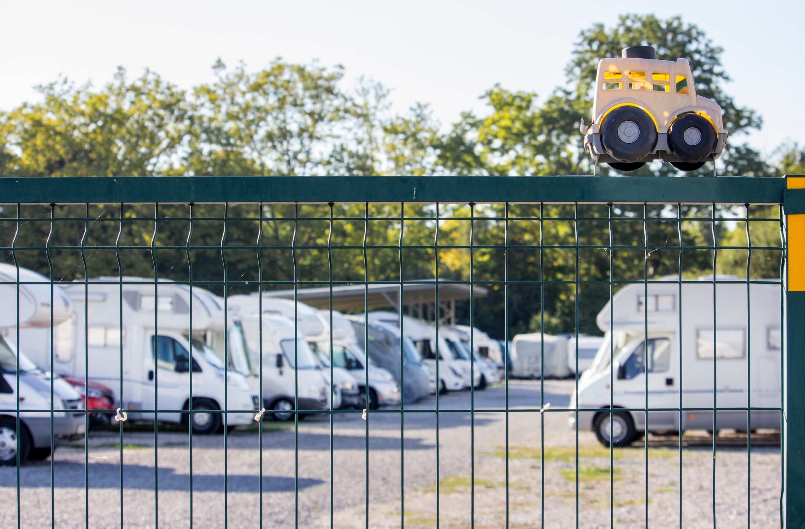 Row of recreational vehicles behind fence on sunny