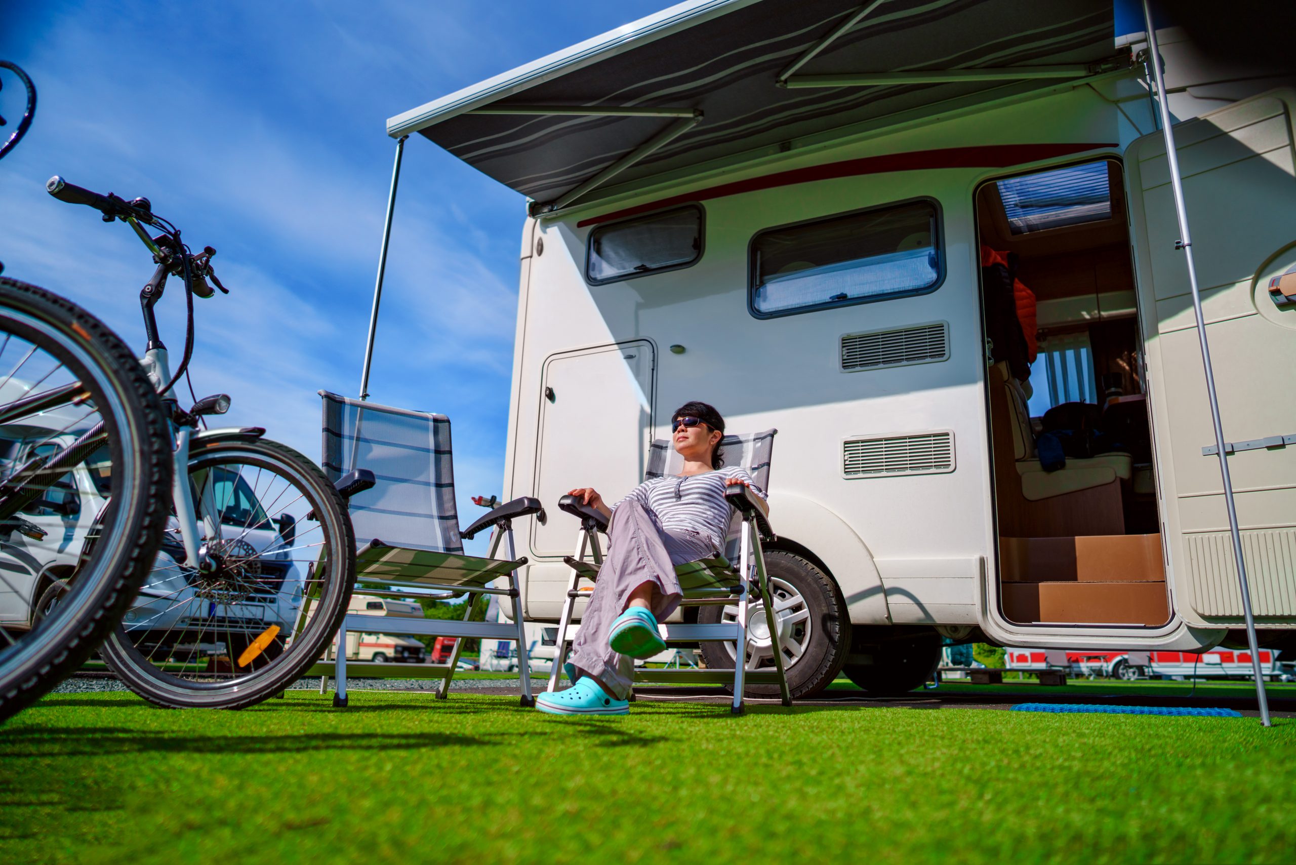 Woman relaxing outside camper with bikes in summer